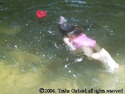 Child swimming toward flower