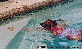 Child swimming toward toys